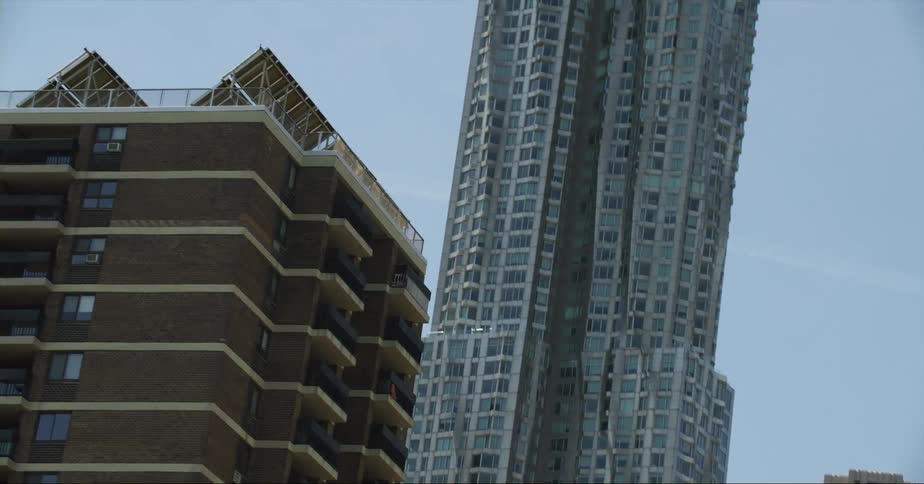 A tower stands tall in the city and high above an apartment building with balconies