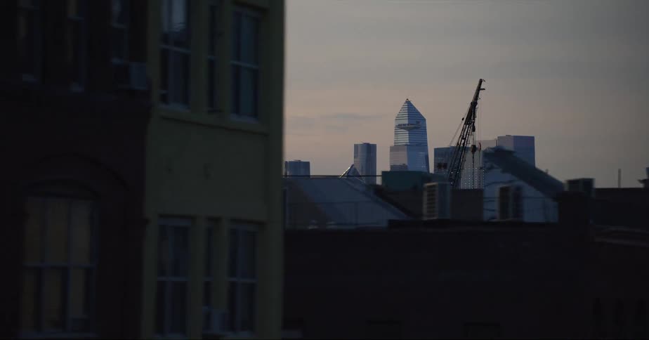 Moving across town towers and skyscrapers and be seen in the distance and a construction crane stands nearby