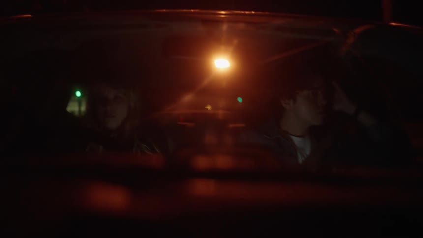 A man drives a car and looks out the side window as he sits beside a woman and they do not talk