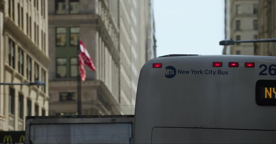 A bus traveling down a street in new york city in the daytime