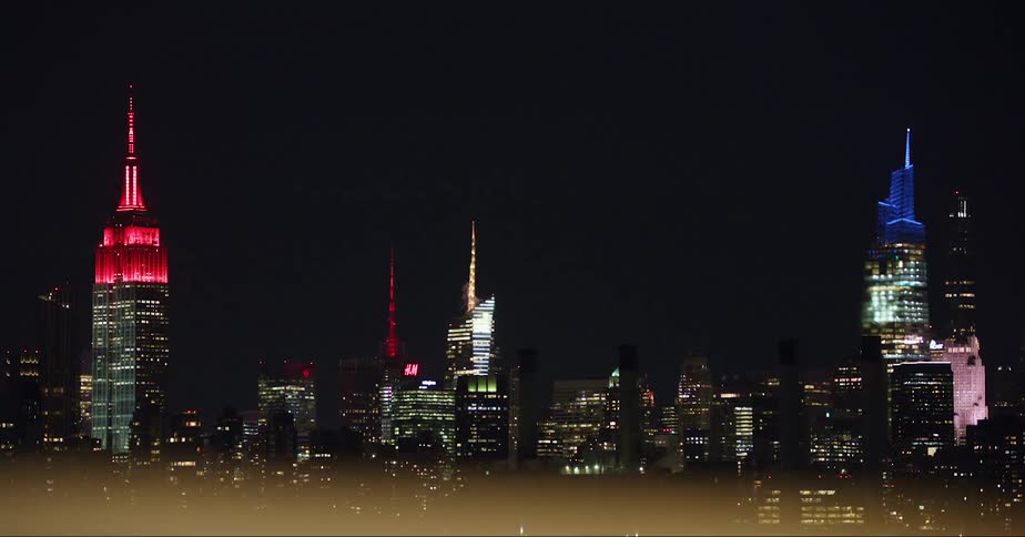 The new york city skyline at night with the empire state building lit red