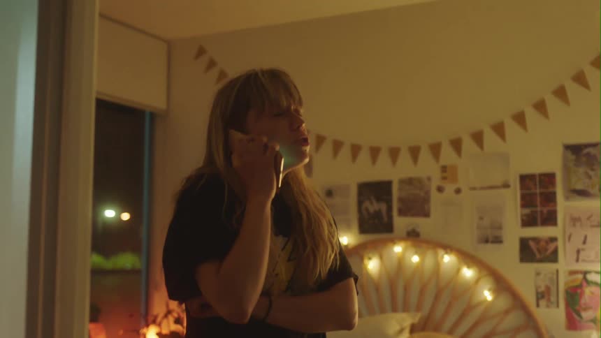 Young nervous woman standing in her bedroom impatiently calls on her cellphone at night
