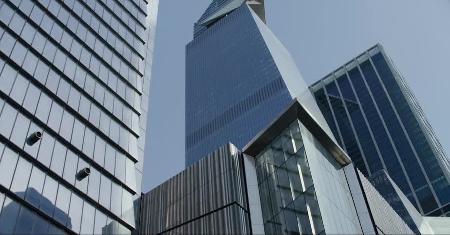 Light reflects on the mirror windows of downtown skyscrapers and a building with unusual architecture stands tall in the city sky