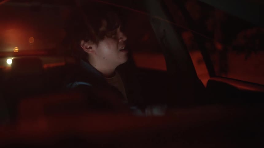 Man with denim jacket and white shirt pulls off the road and gets out of car crying