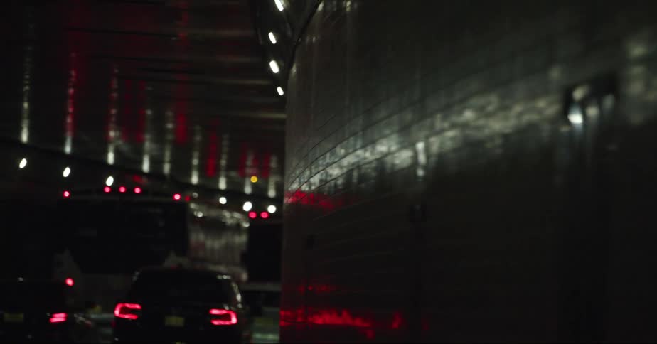 Traffic moves through dark tunnel with reflective tiles on wall