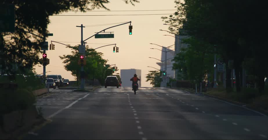 Man with helmet and red jacket rides bike on highway doing front wheel lift at dusk