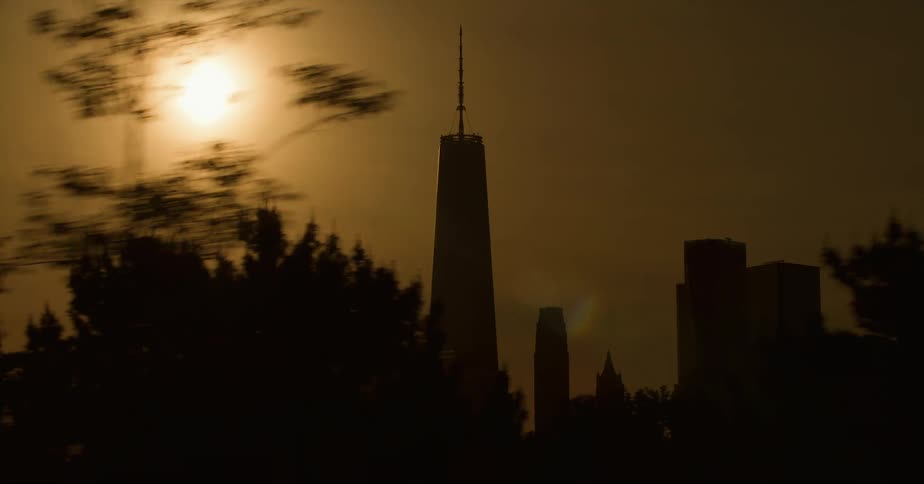 Sun colors hazy sky amber and casts skyscrapers and trees into silhouettes
