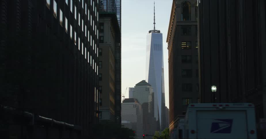 Skyscraper with spire seen from city street at dusk