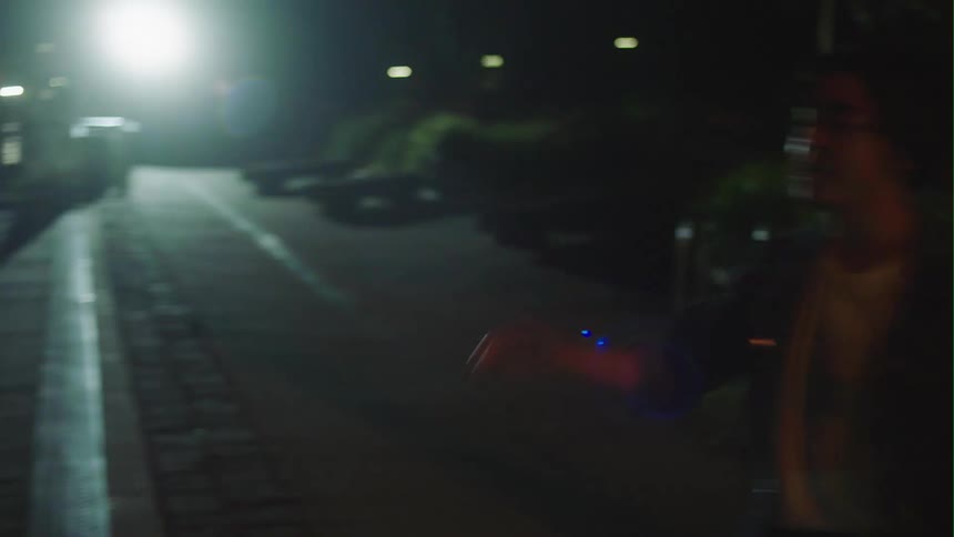 Blonde woman with black coat fights man wearing denim jacket and white shirt near sea in the city at night