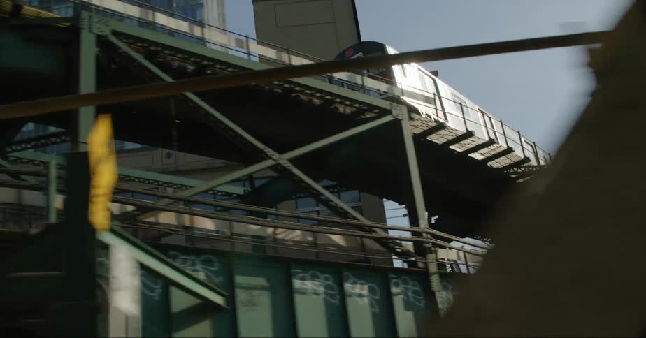 A train travels on a bridge around downtown with tall city buildings in the distance