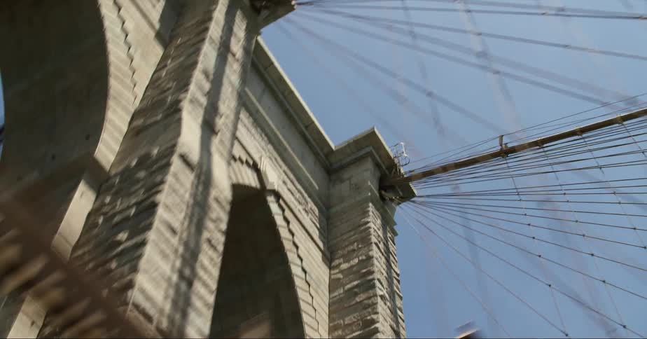 Vehicle crosses suspension bridge through the tower against the sky