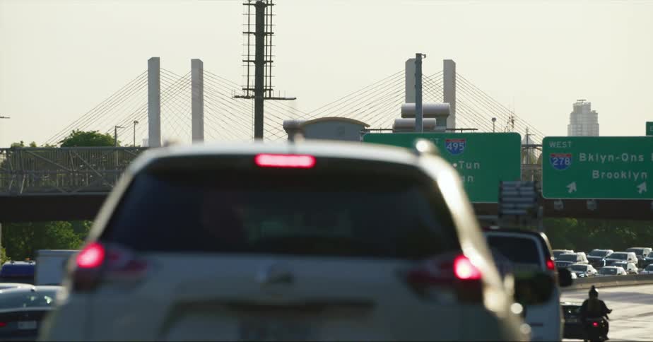 Vehicle drives on divided highway with a view of bridge and skyline
