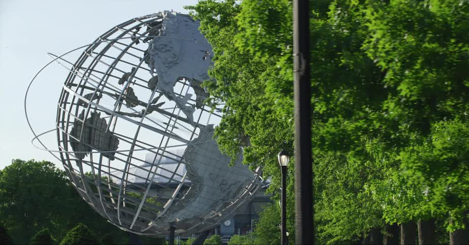 The unisphere spherical stainless steel monument in new york city behind trees