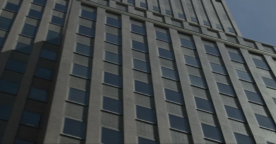 A towering building with countless windows stands tall beneath a sunny sky