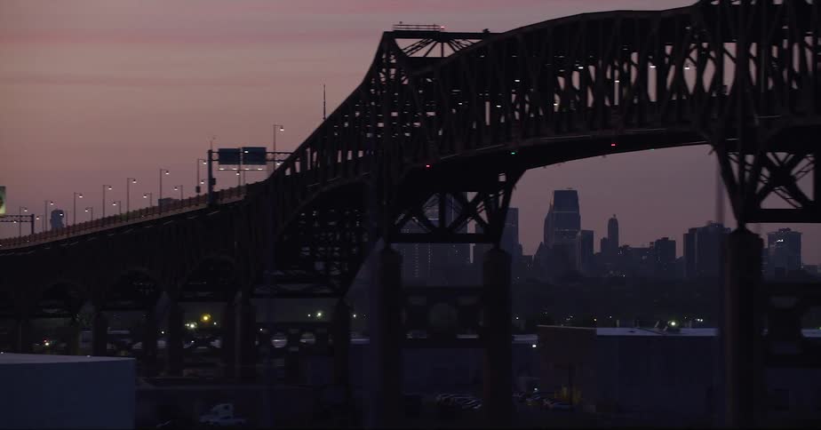 Silhouetted city skyscrapers and a large bridge at sunset