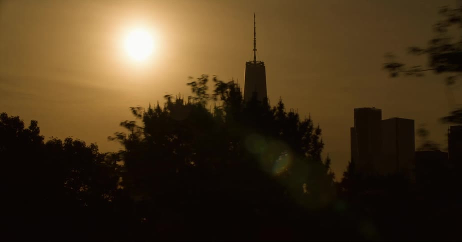 The sun is setting in the horizon of a downtown city