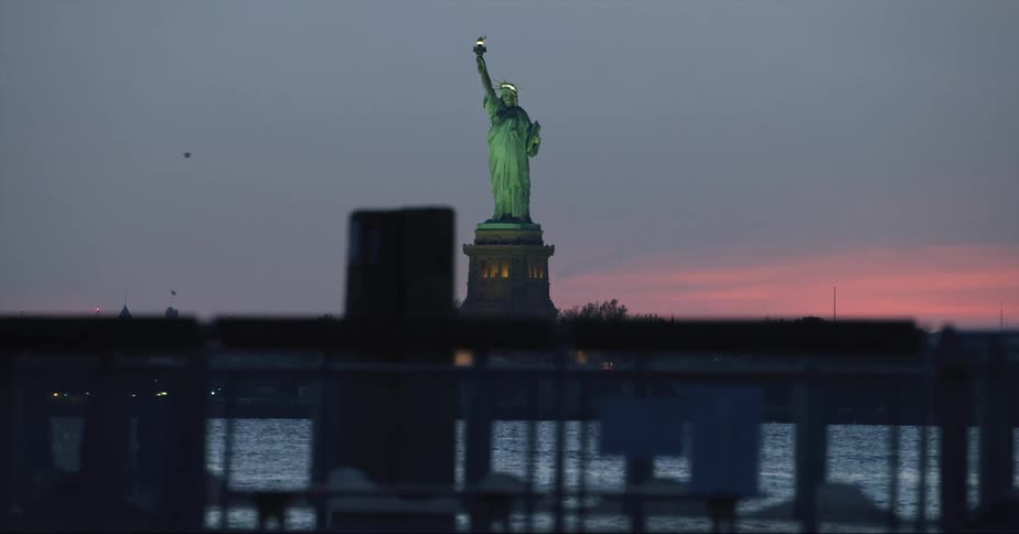 Silhouette of a man walking and the statue of liberty standing tall in the distance