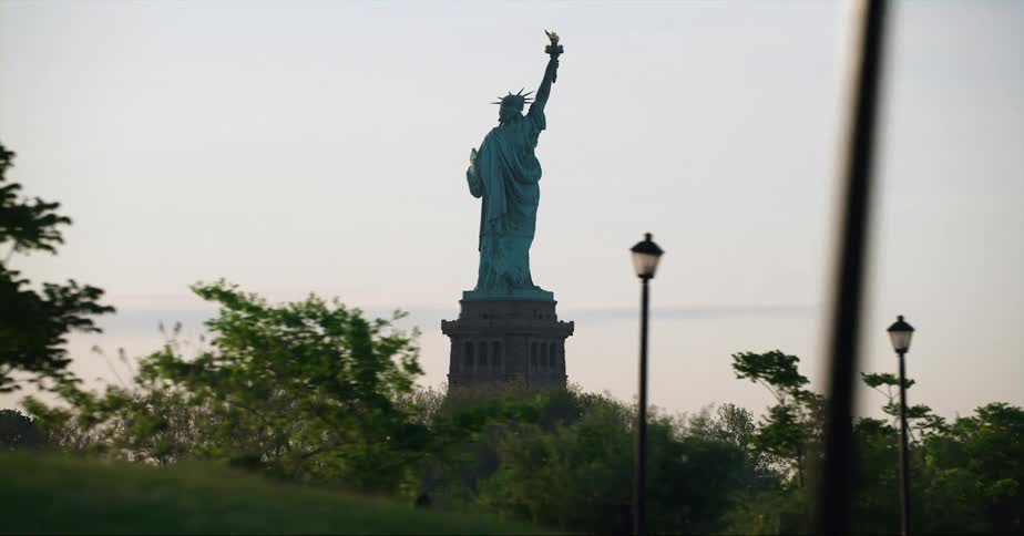 Statue of liberty in the new york city harbor filmed at evening from a moving vehicle