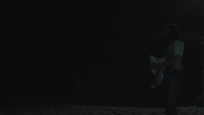 A man taking off a shirt while standing outside in the darkness at night