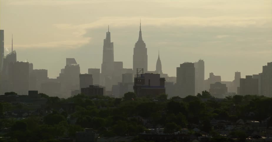 Distant view of skyscraper with spire and high rise buildings in fog in the city