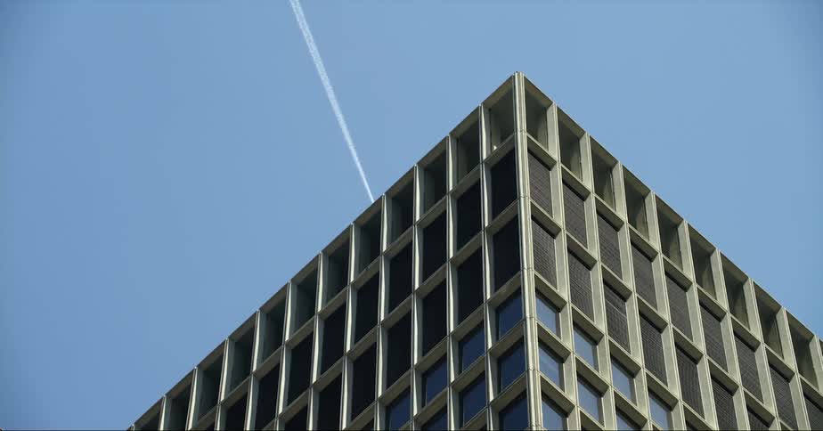 Jet leaves contrail as it passes over office building