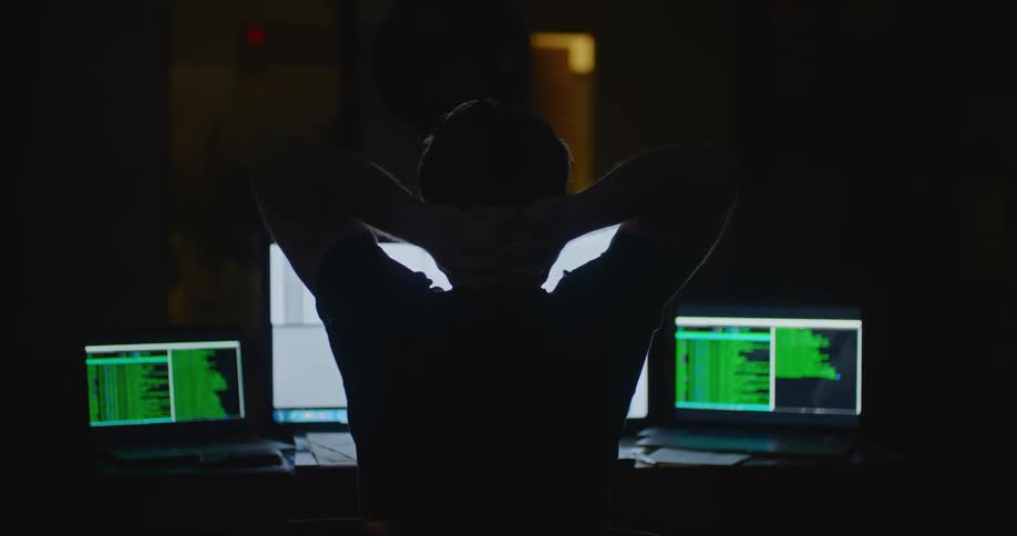 A man stretches his arms behind his head while sitting at his desk