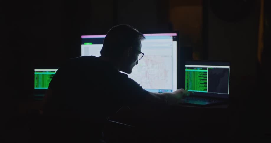 There is a white man working by a bunch of computers