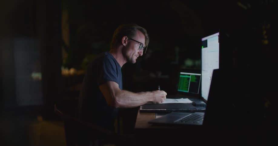 A man is looking at a computer at his desk