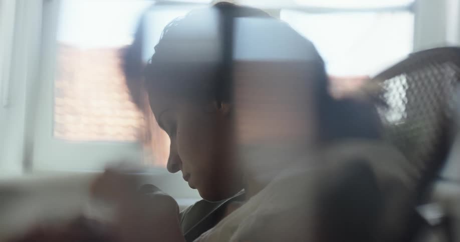 Mother sits in rocking chair near window with her baby