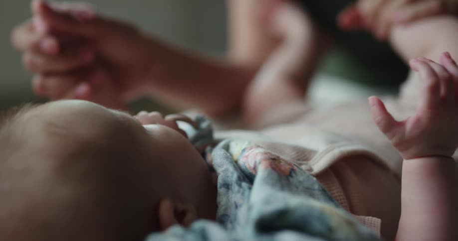 Mother holds babys feet with apron and pacifier