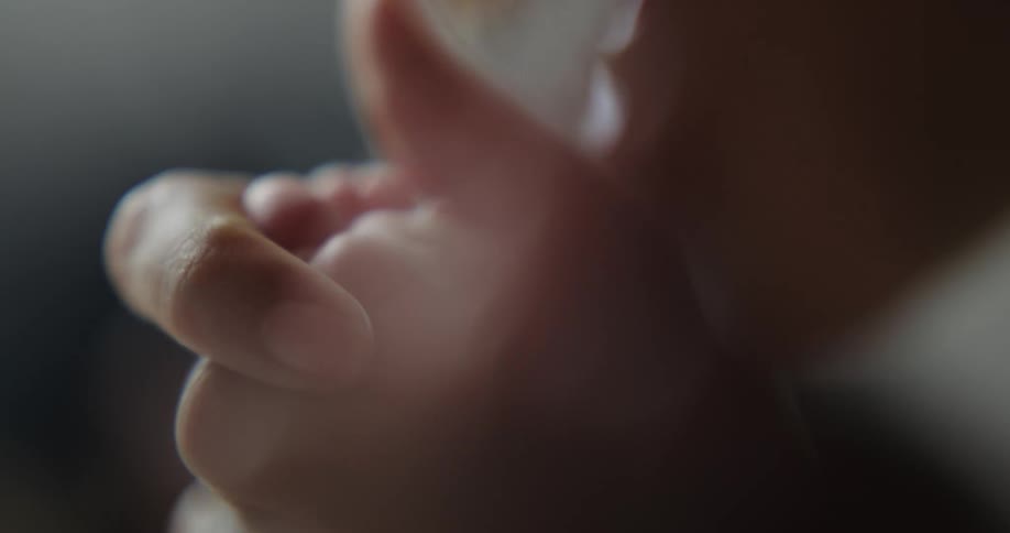 A mom holds her babys tiny foot and bends to kiss it
