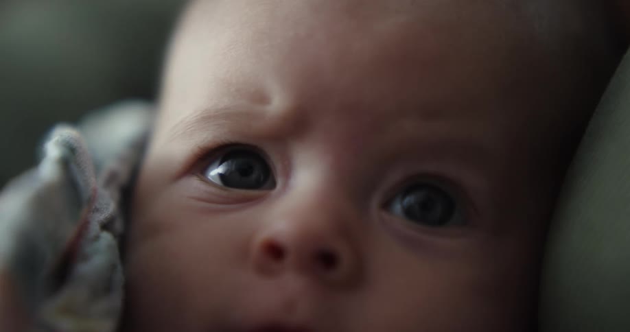 A baby cuddled and held opens his mouth when he sees a pacifier