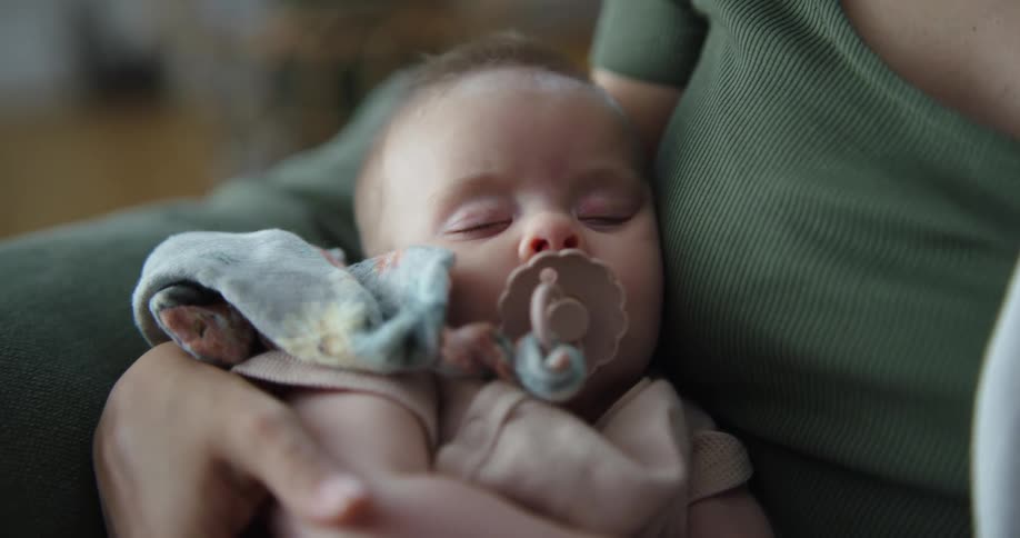 Mother rocks baby sleeping with a pacifier