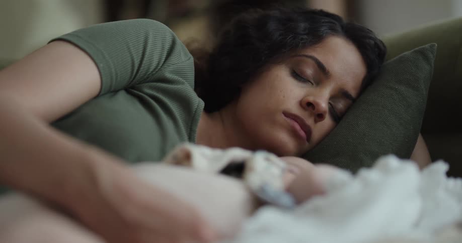 A woman naps with her baby on the couch