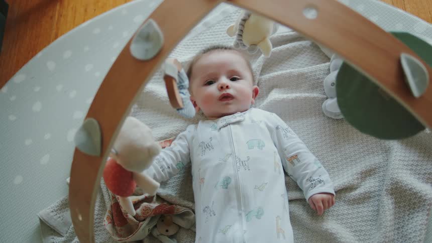 Baby looking up at mobile over crib raises their feet