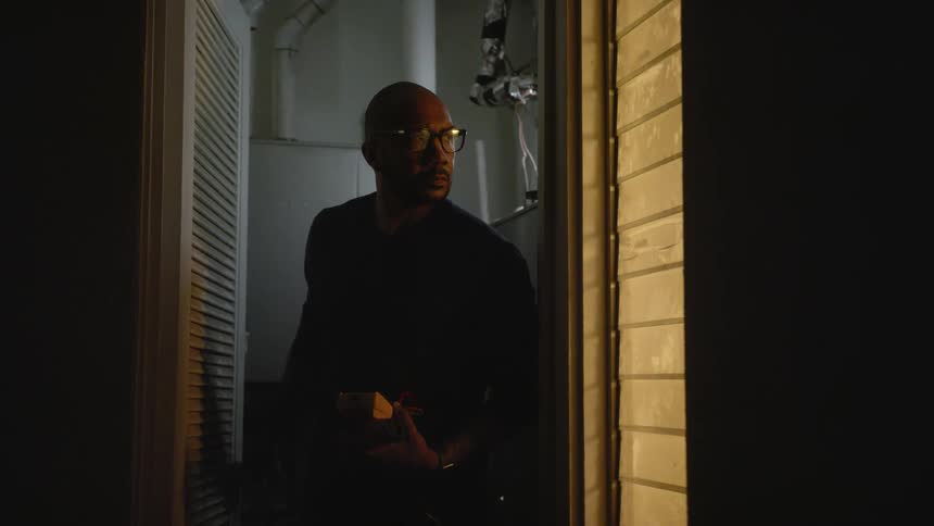 Technician closes the door of a service closet and walks into a dark hallway