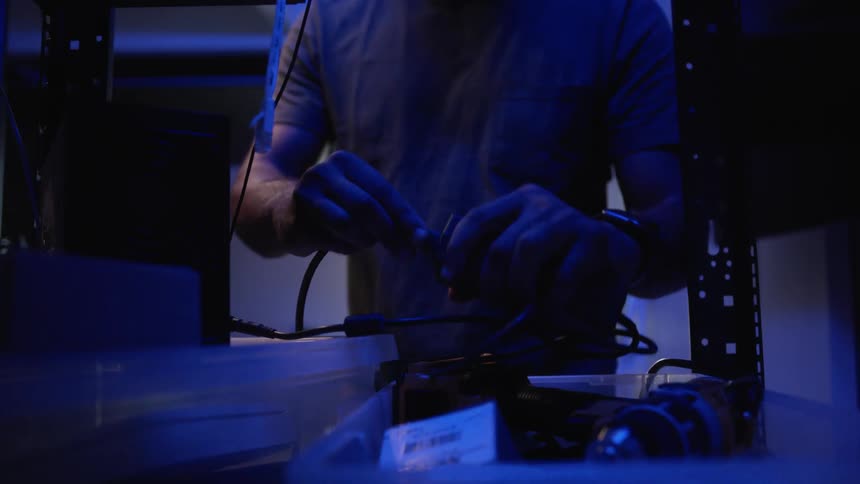 A man reorganizes electrical wires at his desk