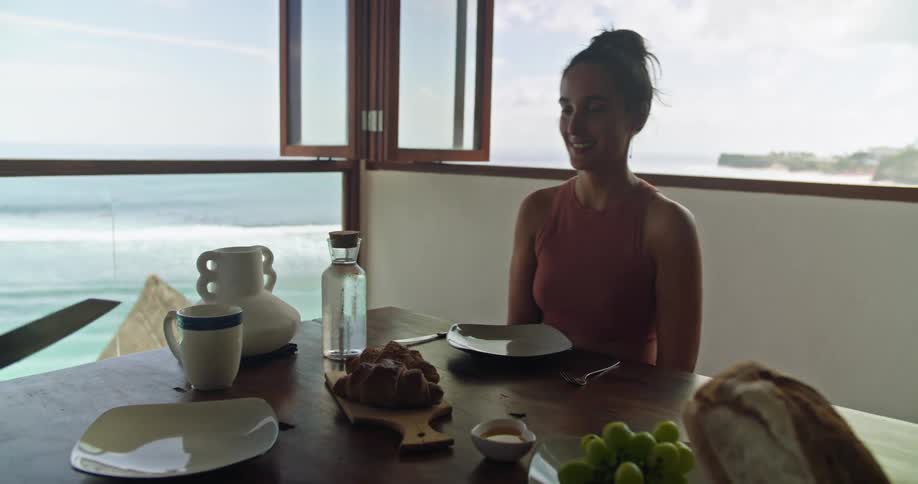 A man places a cutting board with food onto the table in front of his female companion