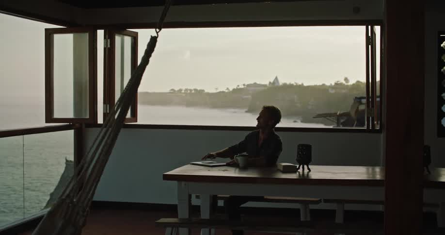 A man sits down to work on his laptop in a houseboat