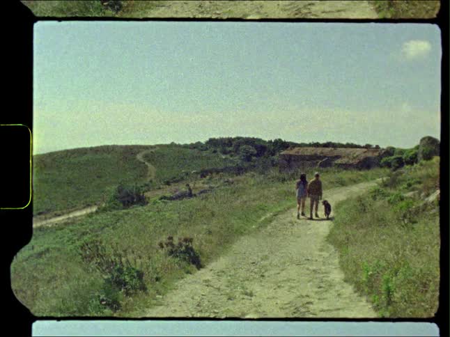 Man and woman walk dog on dirt road in the hills