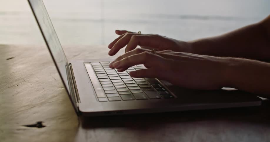 Woman with rings types on laptop keyboard