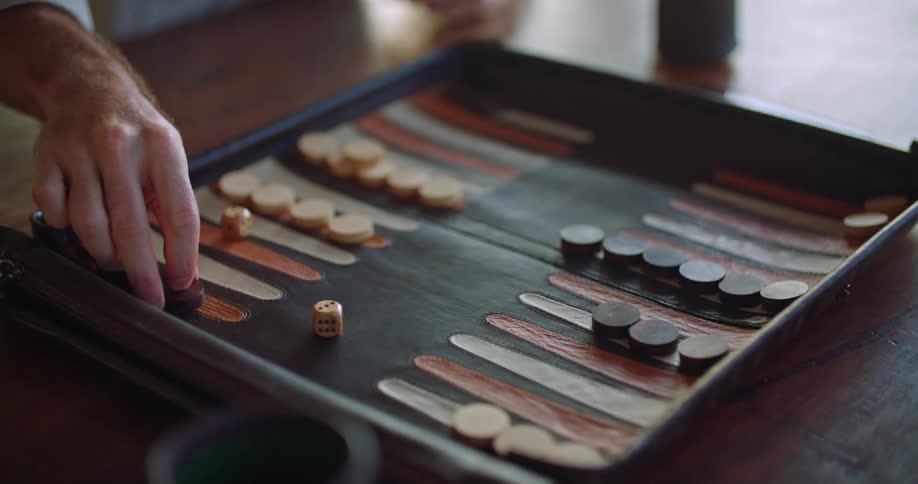 A man rolls the dice and moves his backgammon pieces