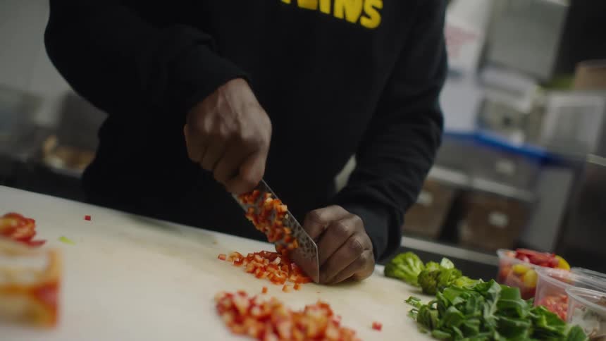 A person is in a kitchen and cutting vegetables