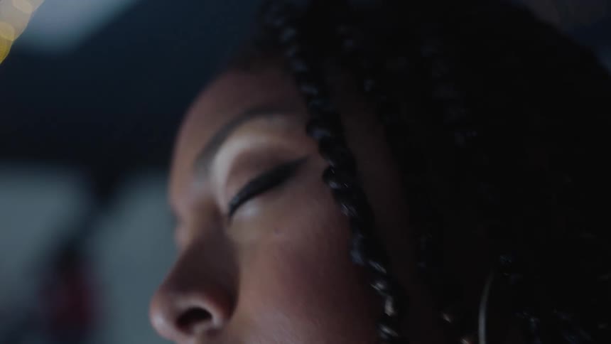 A young black woman moves her head to music