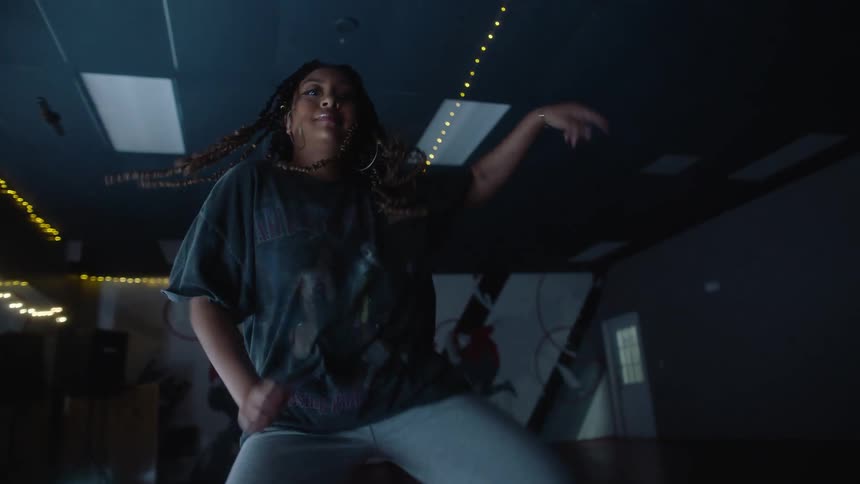 Woman with dreadlocks gray t shirt and pants dances in room