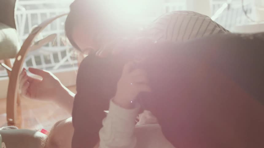 A woman laughs as her dog comes over to her and son on the floor