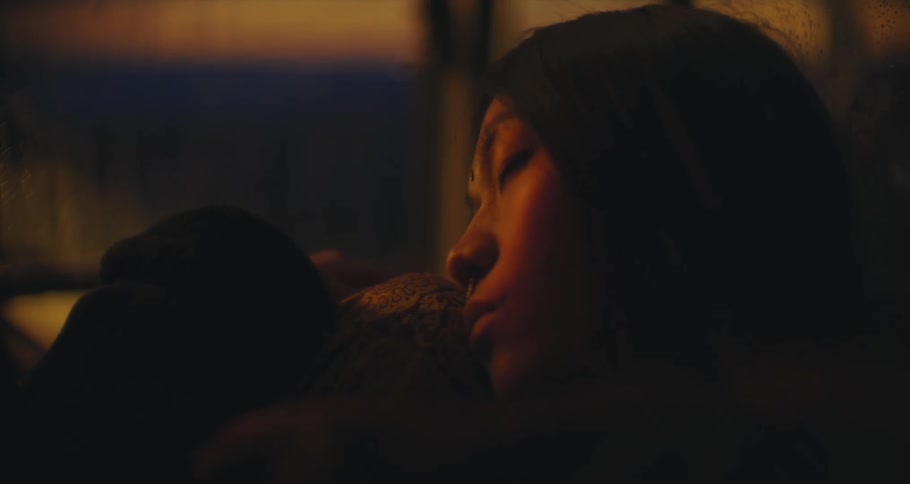 An Asian woman relaxes in her car at sunset