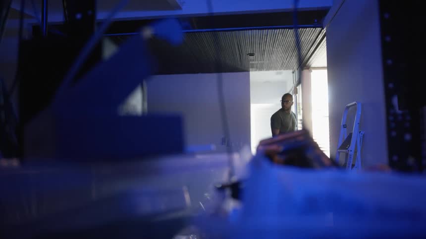 A man looks around a store room or garage and then walks back out