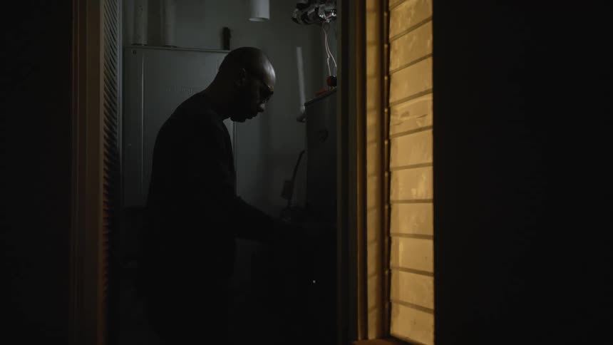 Man removes panel in dim room to work on electronics