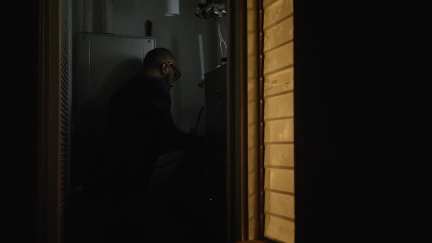 Man working on electronics replaces panel and then closes door to electrical closet